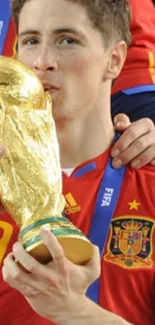 Football player in red jersey kissing trophy in celebration.