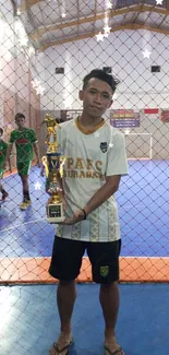 Sportsman holds a trophy on a futsal court.