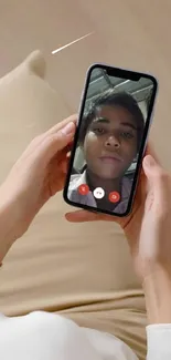 Person holding smartphone with video call wallpaper.