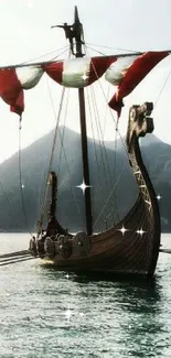 Viking ship with red sails on a calm blue sea.