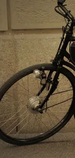 Close-up of a vintage bicycle wheel against a textured wall.