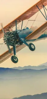 Vintage biplane soaring above misty mountains in scenic view.