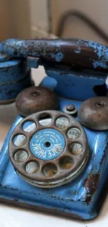 Rustic vintage blue rotary phone on a white surface.