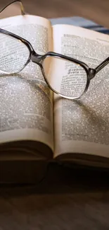 Open book and reading glasses on wooden table.