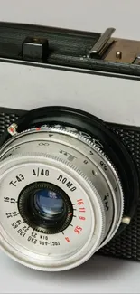 Close-up of vintage camera with lens focus on gray background.