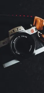 Vintage camera with leather straps on a dark background.