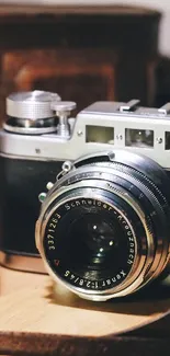 A vintage camera with Ilford film box on wooden table.