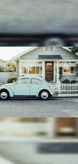 Vintage teal car parked by a cozy house with white picket fence.