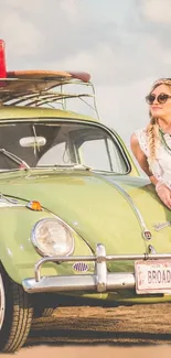 Vintage green car with free-spirited woman leaning against it.