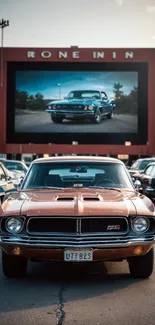 Classic muscle car parked at a drive-in theater under the evening sky.