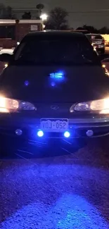 Vintage car with neon lights at night in an urban setting.