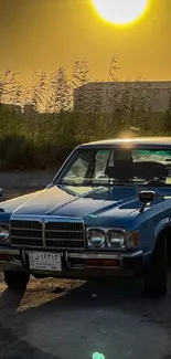 Vintage blue car under golden sunset, rural backdrop.