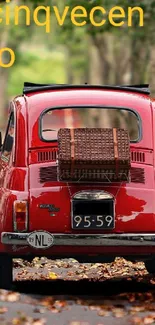 Vintage red car driving through autumn forest path.