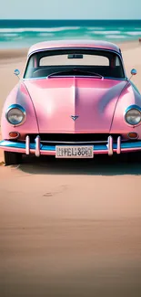 Vintage pink car parked on a sunny beach with an ocean backdrop.