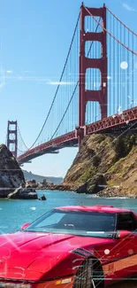 Vintage red car by Golden Gate Bridge under a blue sky.