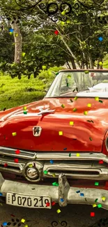 Vintage red car with colorful confetti in nature setting.