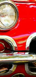 Close-up of a vintage car's red front with chrome details and headlight.