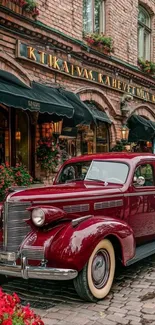 Vintage red car on cobblestone street with historic café background.