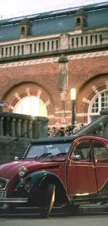 Vintage red car parked near a historic brick building.