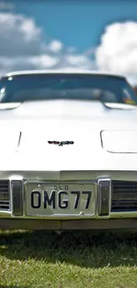 A classic white muscle car set against a bright, cloudy sky.