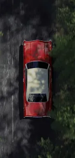 A vintage red car drives on a scenic forest road.