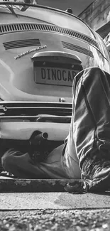 Monochrome photo of a vintage car being repaired.