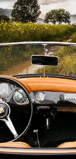Vintage car on scenic road amidst greenery and open sky.