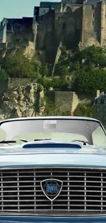 Vintage car in front of a historic castle with clear blue sky.