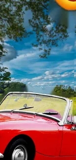 Red vintage convertible under a blue sky with green scenery.