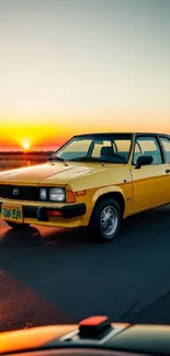 Yellow vintage car driving at sunset on an open road.