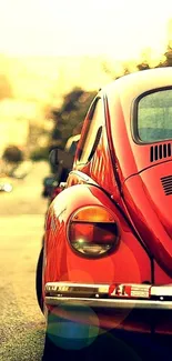 Vintage red beetle car on a city street at sunset, in warm tones.