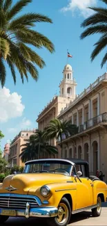 Vintage yellow car with palm trees and historic buildings under a blue sky.