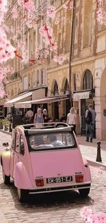 Pink vintage car on a blossom-lined street.