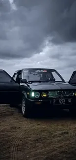 Vintage car with doors open under stormy, cloudy sky on a nighttime coastal road.