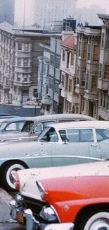 Vintage cars lined up on a sloped urban street with classic buildings.