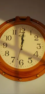 Round vintage wooden clock on wall background.