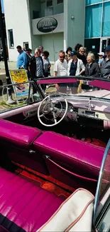 Vintage car with purple interior at urban event.