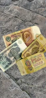 Vintage currency bills on a textured stone background.