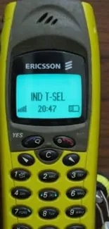 Yellow Ericsson mobile phone on wooden table.