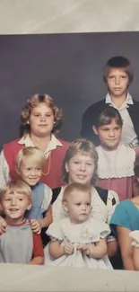 A vintage family portrait featuring children in 1980s attire against a gray backdrop.