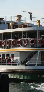 Vintage ferry sailing on water with seagulls in the background.