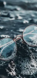 Vintage round glasses on rocky beach in aqua tones.