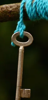 Vintage key hanging on a blue rope against a dark background.