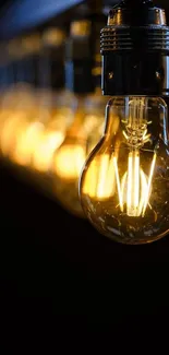 Vintage lightbulb with warm glowing filament on a dark background.