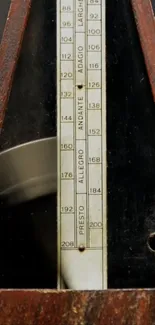 Close-up of a vintage wooden metronome with visible tempo markings.