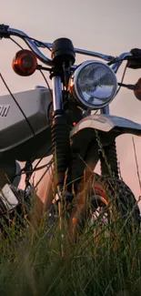 Vintage motorcycle at sunset in a grassy field.