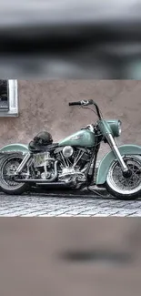 Vintage motorcycle with sage green color against a rustic wall.