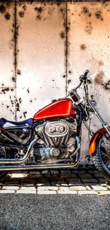 A vintage red motorcycle against an urban wall.