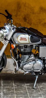 Vintage motorcycle against orange wall, perfect for mobile wallpaper.