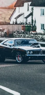 Classic black muscle car parked by country house.